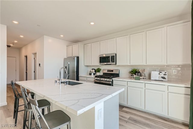 9564 Archer Peak Ct, Las Vegas, NV 89143 - kitchen with appliances with stainless steel finishes, a sink, a center island with sink, recessed lighting, and light wood-style floors