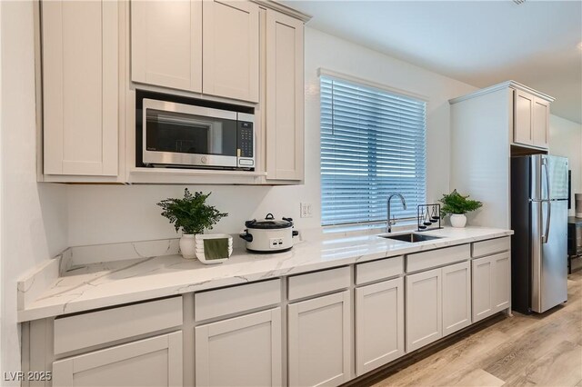 9564 Archer Peak Ct, Las Vegas, NV 89143 - kitchen featuring appliances with stainless steel finishes, a sink, light wood-style flooring, and light stone counters