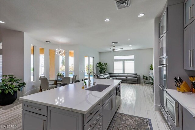 271 E Shelbourne Ave, Las Vegas, NV 89123 - kitchen with gray cabinets, a sink, open floor plan, appliances with stainless steel finishes, and a kitchen island with sink