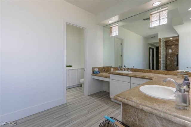271 E Shelbourne Ave, Las Vegas, NV 89123 - bathroom featuring double vanity, toilet, wood finished floors, tiled shower, and baseboards