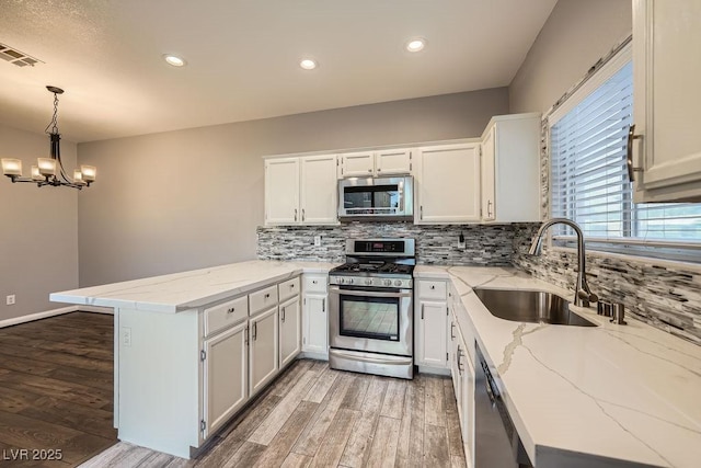3253 Mystic Ridge Ct, Las Vegas, NV 89129 - kitchen featuring appliances with stainless steel finishes, a peninsula, a sink, light wood-style floors, and tasteful backsplash