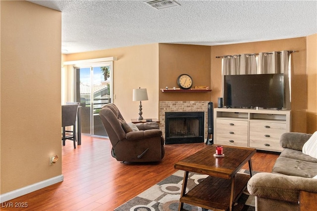 2200 Highpointe Dr Unit 202, Laughlin, NV 89029 - living area featuring wood finished floors, a brick fireplace, a textured ceiling, and baseboards