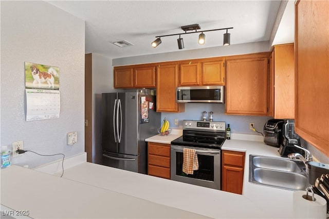 2200 Highpointe Dr Unit 202, Laughlin, NV 89029 - kitchen featuring appliances with stainless steel finishes, a sink, light countertops, brown cabinets, and a peninsula