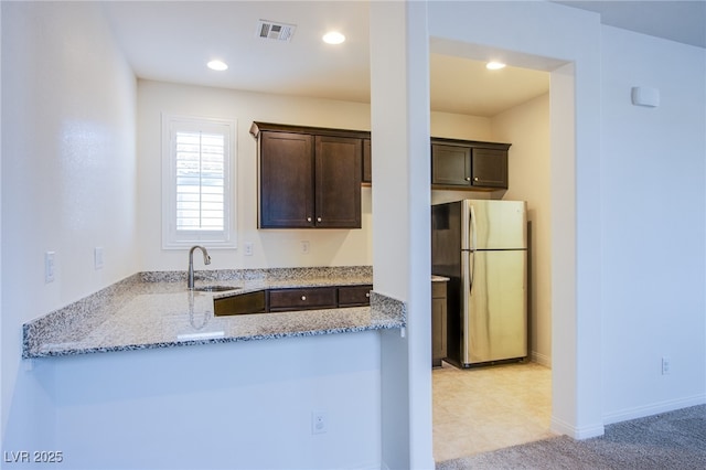 8665 Jerlyn St, Las Vegas, NV 89113 - kitchen with freestanding refrigerator, dark brown cabinets, light stone counters, a peninsula, and recessed lighting
