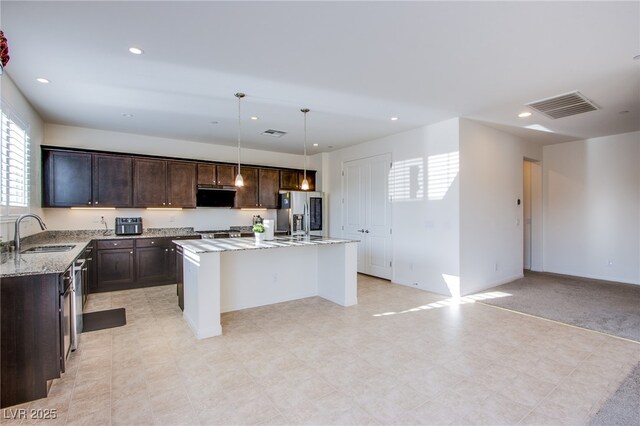 8665 Jerlyn St, Las Vegas, NV 89113 - kitchen with stainless steel fridge with ice dispenser, dark brown cabinets, light stone countertops, a center island with sink, and recessed lighting