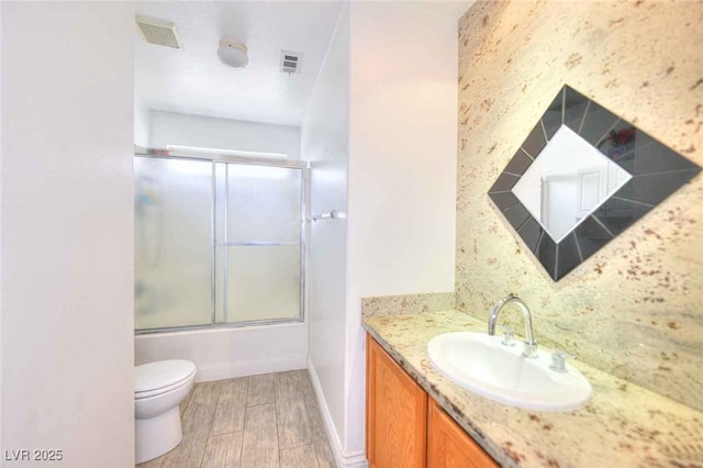 6233 Overhang Ave, Henderson, NV 89011 - full bathroom with wood finished floors, vanity, toilet, enclosed tub / shower combo, and baseboards