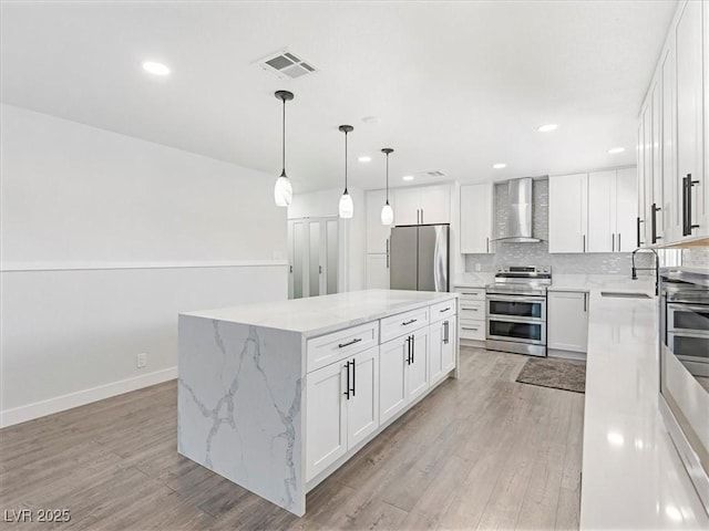 1700 E Oakey Blvd, Las Vegas, NV 89104 - kitchen with appliances with stainless steel finishes, wall chimney range hood, a sink, a center island, and light wood-type flooring