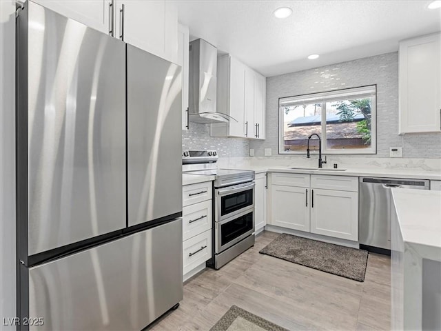 1700 E Oakey Blvd, Las Vegas, NV 89104 - kitchen featuring stainless steel appliances, a sink, wall chimney range hood, tasteful backsplash, and white cabinetry