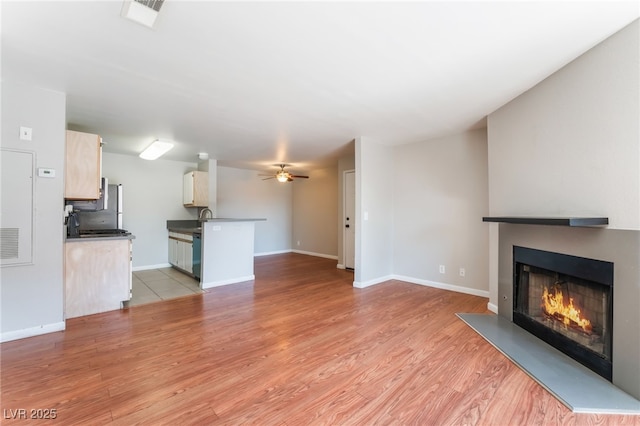2200 S Fort Apache Rd Unit 2015, Las Vegas, NV 89117 - unfurnished living room with a lit fireplace, light wood-style flooring, ceiling fan, and baseboards