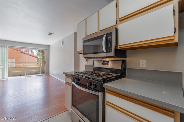 2200 S Fort Apache Rd Unit 2015, Las Vegas, NV 89117 - kitchen featuring stainless steel appliances, baseboards, light wood finished floors, and white cabinets