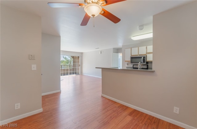 2200 S Fort Apache Rd Unit 2015, Las Vegas, NV 89117 - unfurnished living room featuring baseboards, light wood-style flooring, and ceiling fan