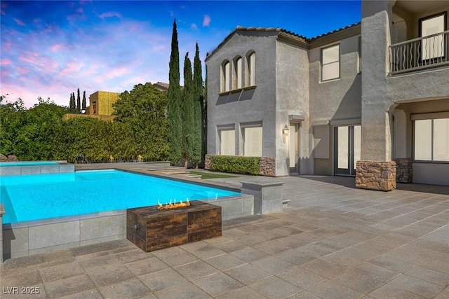 11503 Glowing Sunset Ln, Las Vegas, NV 89135 - pool at dusk with an outdoor pool, a patio area, and an outdoor fire pit