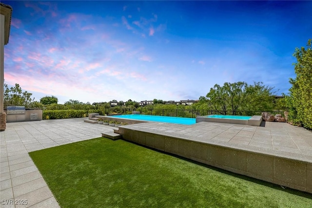 11503 Glowing Sunset Ln, Las Vegas, NV 89135 - pool at dusk featuring an outdoor kitchen and a patio area