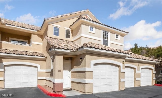 5855 Valley Dr Unit 1070, North Las Vegas, NV 89031 - view of front of home featuring an attached garage, a tile roof, stucco siding, and asphalt driveway