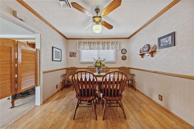 22 Jade Cir, Las Vegas, NV 89106 - dining space with wood finished floors, a ceiling fan, a wainscoted wall, a textured ceiling, and crown molding