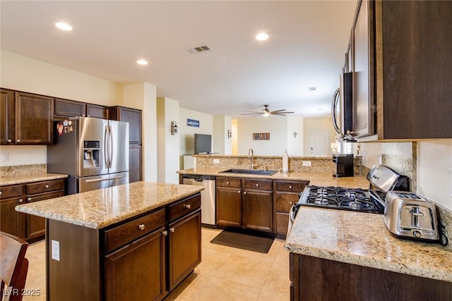 7611 Redcloud Peak St, Las Vegas, NV 89166 - kitchen featuring appliances with stainless steel finishes, a sink, a peninsula, a ceiling fan, and light stone counters
