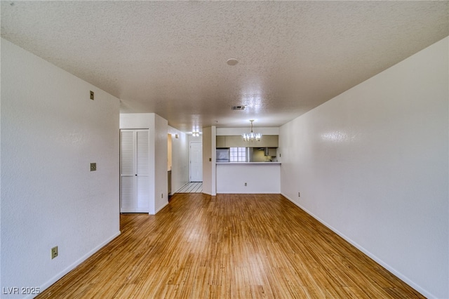 2040 Mesquite Ln Unit 203, Laughlin, NV 89029 - unfurnished living room featuring a chandelier, a textured ceiling, wood finished floors, and baseboards