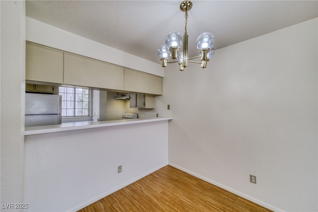 2040 Mesquite Ln Unit 203, Laughlin, NV 89029 - kitchen featuring freestanding refrigerator, wood finished floors, baseboards, a chandelier, and under cabinet range hood