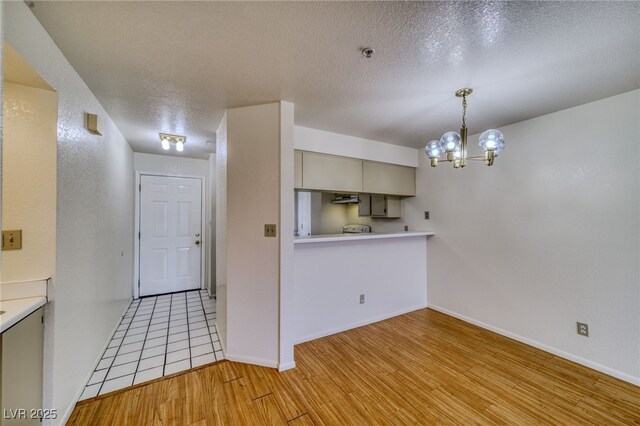 2040 Mesquite Ln Unit 203, Laughlin, NV 89029 - kitchen with light wood-style floors, a chandelier, a textured ceiling, light countertops, and pendant lighting