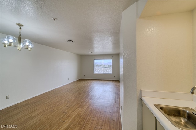 2040 Mesquite Ln Unit 203, Laughlin, NV 89029 - unfurnished room featuring wood finished floors, a pendent fire sprinkler, a sink, a chandelier, and baseboards