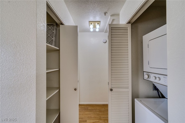 2040 Mesquite Ln Unit 203, Laughlin, NV 89029 - laundry area with stacked washing machine and dryer, wood finished floors, a textured ceiling, baseboards, and a textured wall
