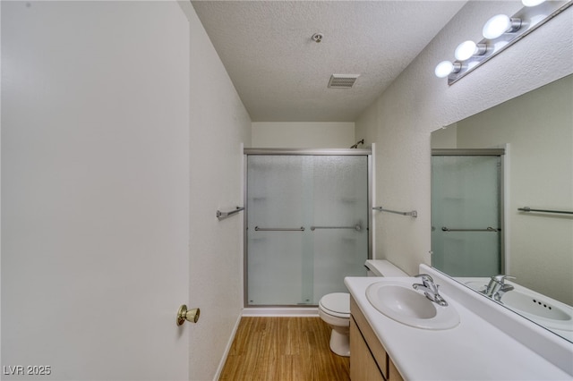 2040 Mesquite Ln Unit 203, Laughlin, NV 89029 - bathroom with toilet, a stall shower, vanity, wood finished floors, and a textured ceiling