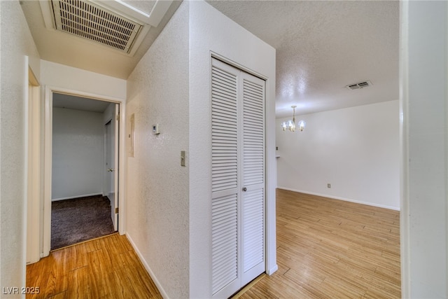 2040 Mesquite Ln Unit 203, Laughlin, NV 89029 - hallway with a chandelier, light wood-style flooring, a textured wall, and baseboards