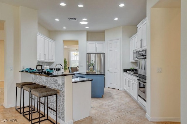 4845 Santo Romeo St, Las Vegas, NV 89135 - kitchen featuring a peninsula, a breakfast bar, stainless steel appliances, light tile patterned flooring, and a kitchen island