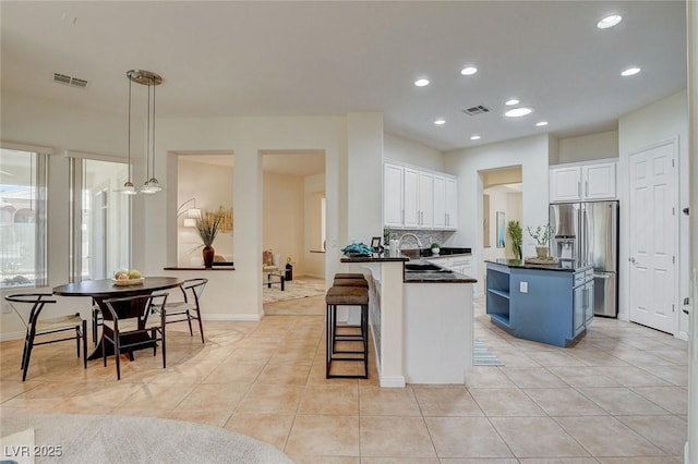 4845 Santo Romeo St, Las Vegas, NV 89135 - kitchen featuring stainless steel fridge, dark countertops, white cabinetry, light tile patterned floors, and a kitchen breakfast bar