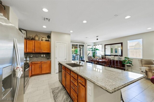 703 Shiva St, Las Vegas, NV 89178 - kitchen featuring a sink, stainless steel appliances, a breakfast bar, light stone counters, and a kitchen island with sink