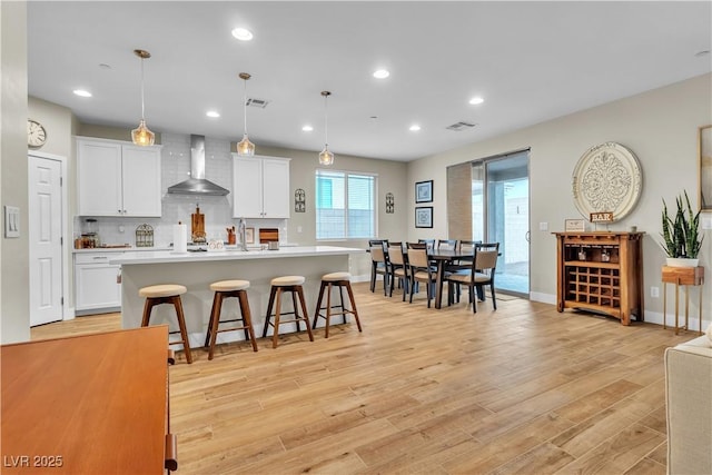 741 Monroe Hill Pl, Henderson, NV 89011 - kitchen featuring wall chimney range hood, light countertops, white cabinetry, an island with sink, and recessed lighting