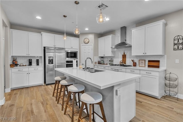 741 Monroe Hill Pl, Henderson, NV 89011 - kitchen featuring appliances with stainless steel finishes, wall chimney exhaust hood, a sink, tasteful backsplash, and a kitchen breakfast bar
