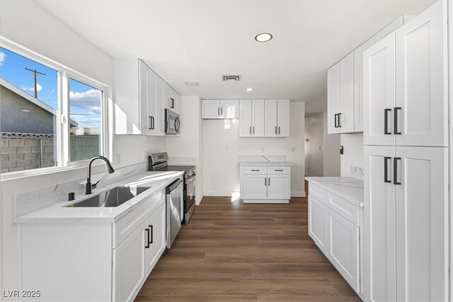 704 Slayton Dr, Las Vegas, NV 89107 - kitchen featuring appliances with stainless steel finishes, a sink, dark wood-style flooring, light stone countertops, and recessed lighting