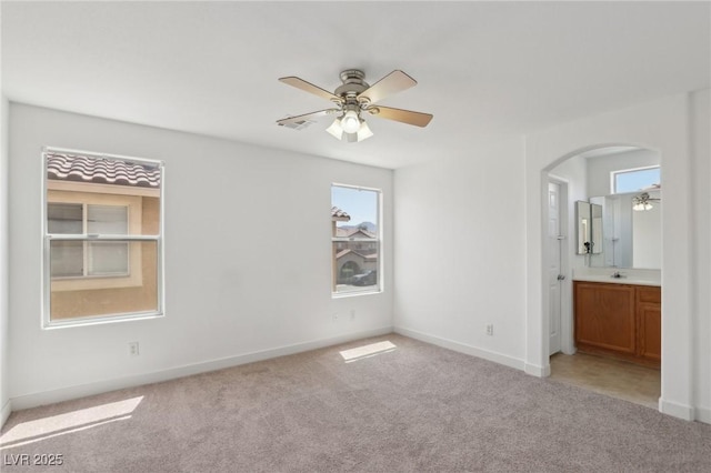 1043 Monte De Oro Ave, Las Vegas, NV 89183 - unfurnished bedroom with light carpet, arched walkways, baseboards, ensuite bath, and ceiling fan