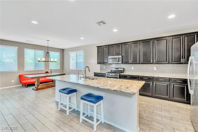 7624 Mallard Bay Ave, Las Vegas, NV 89179 - kitchen with a sink, appliances with stainless steel finishes, decorative backsplash, light stone countertops, and a kitchen breakfast bar