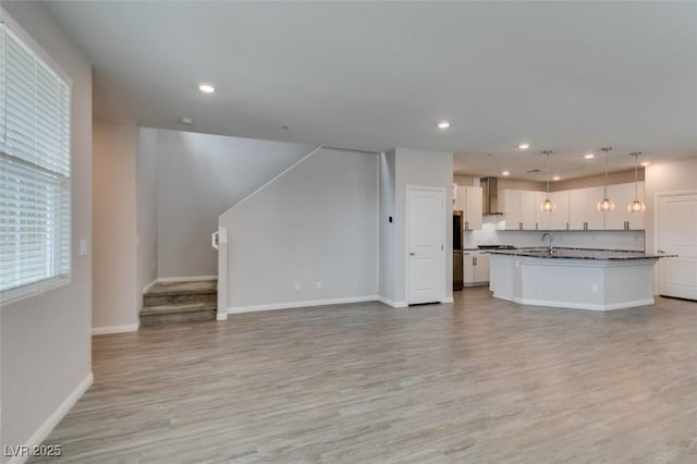 3270 Palindrome Ave, Henderson, NV 89044 - unfurnished living room featuring light wood-style flooring, stairs, recessed lighting, baseboards, and a sink