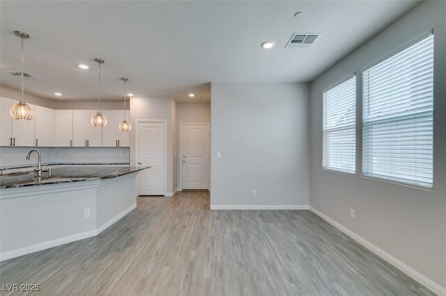 3270 Palindrome Ave, Henderson, NV 89044 - kitchen with a sink, dark stone counters, white cabinets, light wood-style flooring, and recessed lighting