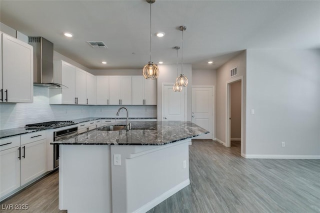 3270 Palindrome Ave, Henderson, NV 89044 - kitchen with wall chimney range hood, a sink, dark stone counters, light wood-style flooring, and stainless steel oven