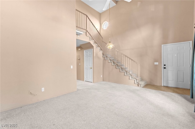 5615 Calais Ct, Las Vegas, NV 89118 - unfurnished living room featuring a towering ceiling, stairs, carpet flooring, ceiling fan, and baseboards