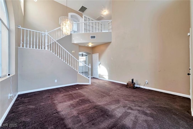 5341 Cool Dawn Ct, Las Vegas, NV 89130 - unfurnished living room with a high ceiling, baseboards, carpet, arched walkways, and a chandelier