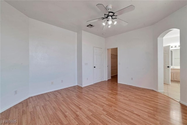 5341 Cool Dawn Ct, Las Vegas, NV 89130 - spare room with arched walkways, a ceiling fan, light wood-style flooring, and baseboards