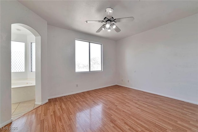 5341 Cool Dawn Ct, Las Vegas, NV 89130 - spare room featuring arched walkways, light wood-type flooring, ceiling fan, and baseboards
