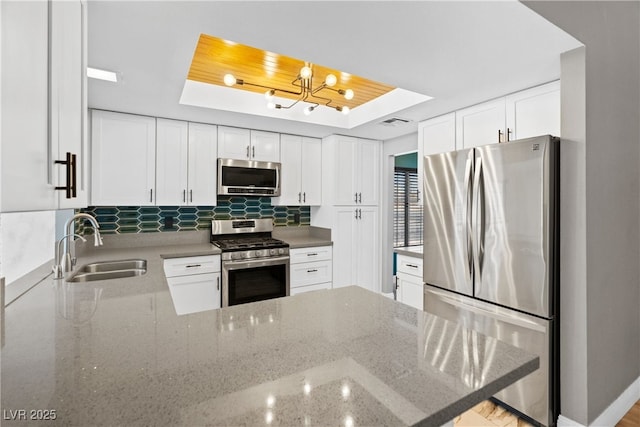 1655 E Hacienda Ave, Las Vegas, NV 89119 - kitchen featuring appliances with stainless steel finishes, a sink, a raised ceiling, a peninsula, and white cabinetry