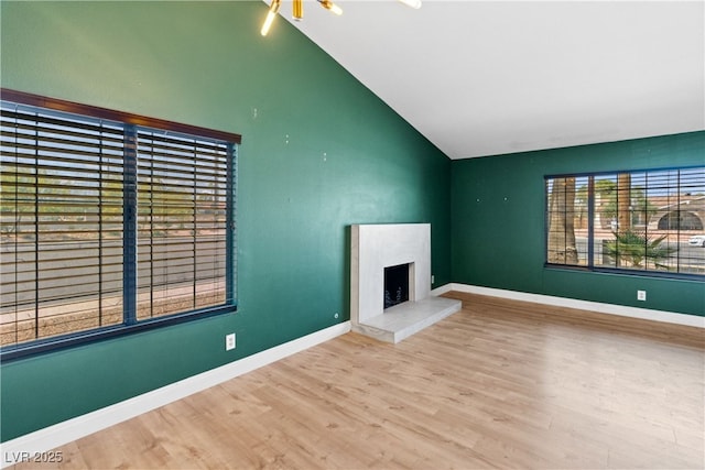 1655 E Hacienda Ave, Las Vegas, NV 89119 - unfurnished living room featuring vaulted ceiling, wood finished floors, a fireplace with raised hearth, and baseboards