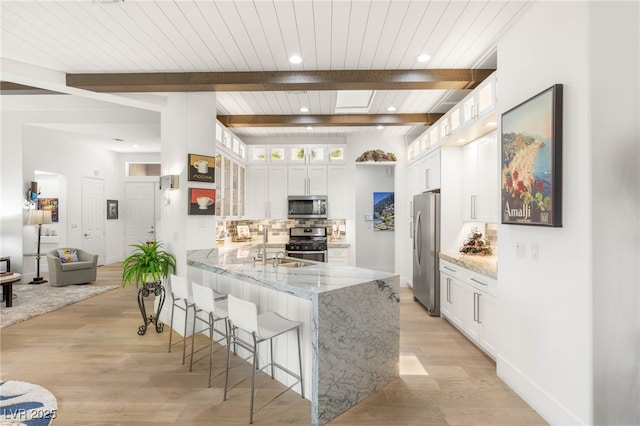 10404 Long Leaf Pl, Las Vegas, NV 89134 - kitchen featuring stainless steel appliances, decorative backsplash, a breakfast bar, white cabinets, and a peninsula