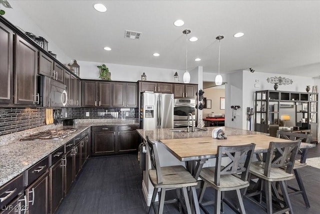 6857 Stone Tower Ct, Las Vegas, NV 89149 - kitchen featuring stainless steel appliances, recessed lighting, dark brown cabinets, light stone counters, and a sink