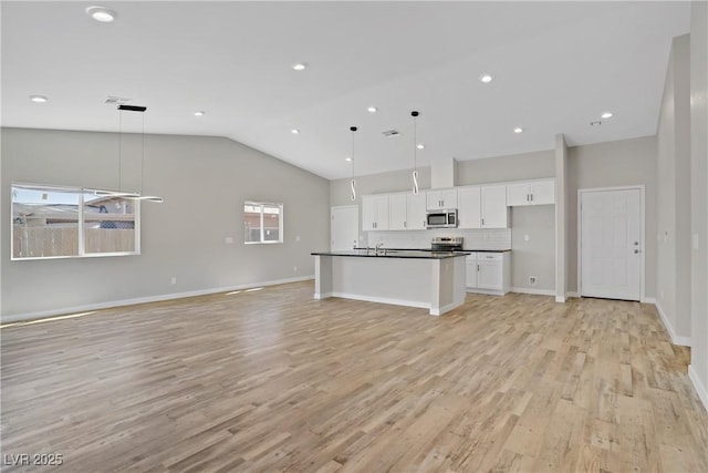 2130 Revere St, North Las Vegas, NV 89030 - kitchen with stainless steel appliances, open floor plan, dark countertops, vaulted ceiling, and white cabinets
