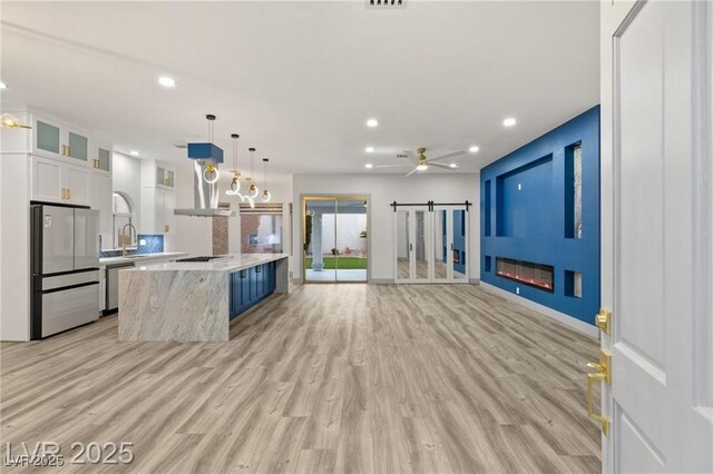 1613 Shadow Rock Dr, Las Vegas, NV 89117 - kitchen with stainless steel appliances, light wood-style flooring, a fireplace, recessed lighting, and white cabinets