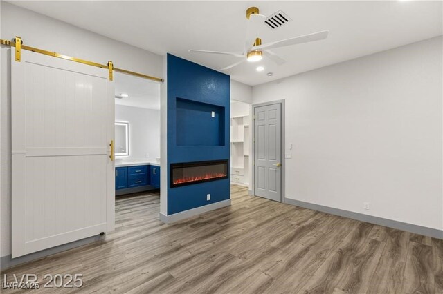 1613 Shadow Rock Dr, Las Vegas, NV 89117 - unfurnished bedroom featuring a large fireplace, wood finished floors, a barn door, baseboards, and recessed lighting