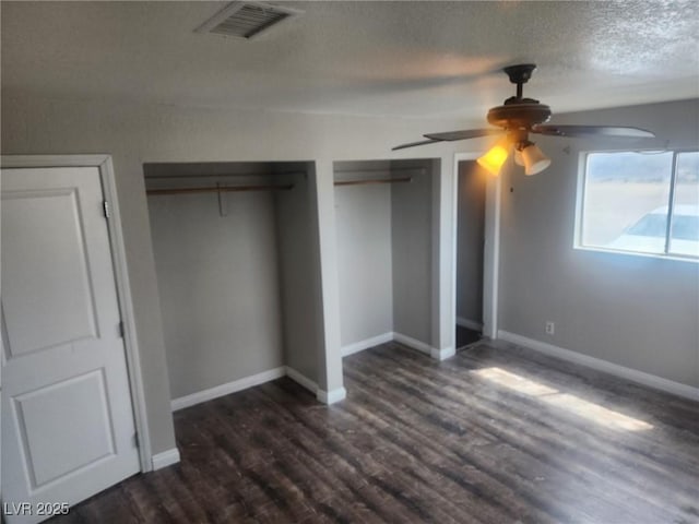 781 Buol Rd, Pahrump, NV 89048 - unfurnished bedroom with dark wood-type flooring, two closets, a textured ceiling, a ceiling fan, and baseboards